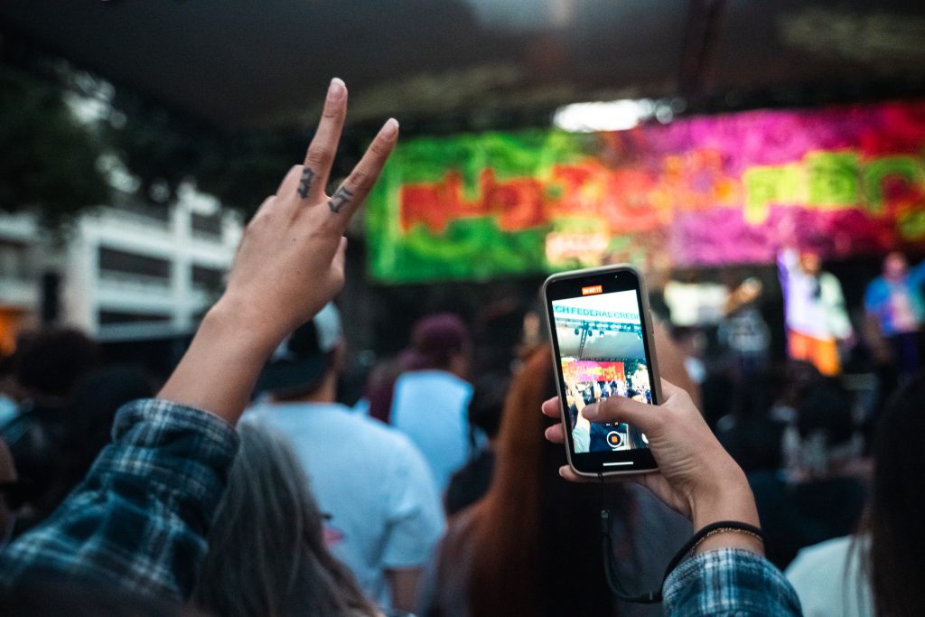 Recording show with smartphone and flashing victory sign